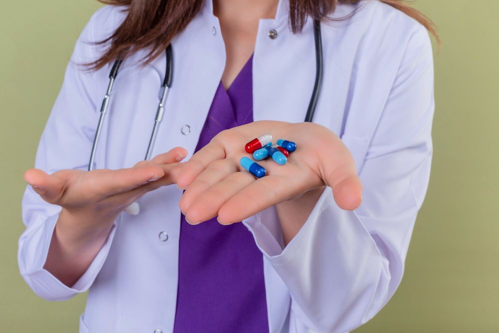 A female doctor is holding a handful of pills in her hand.