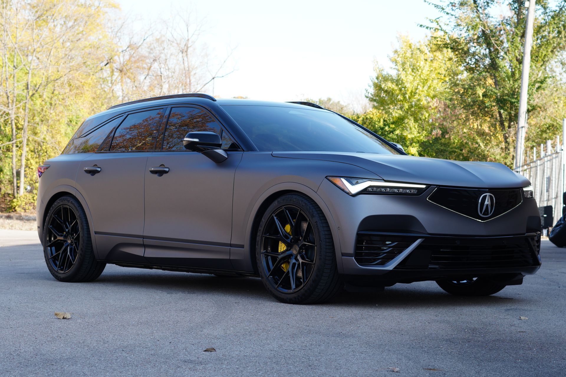 Matte gray Acura SUV with black wheels and yellow brake calipers parked outside.