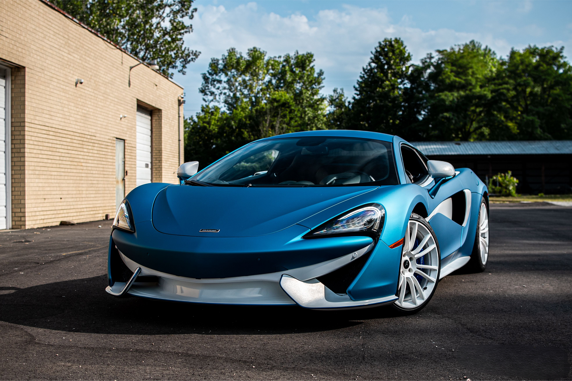 A blue sports car is parked in front of a brick building.