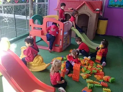 Niños jugando en coloridos juegos infantiles cubiertos, con toboganes, túneles y bloques de juguete.
