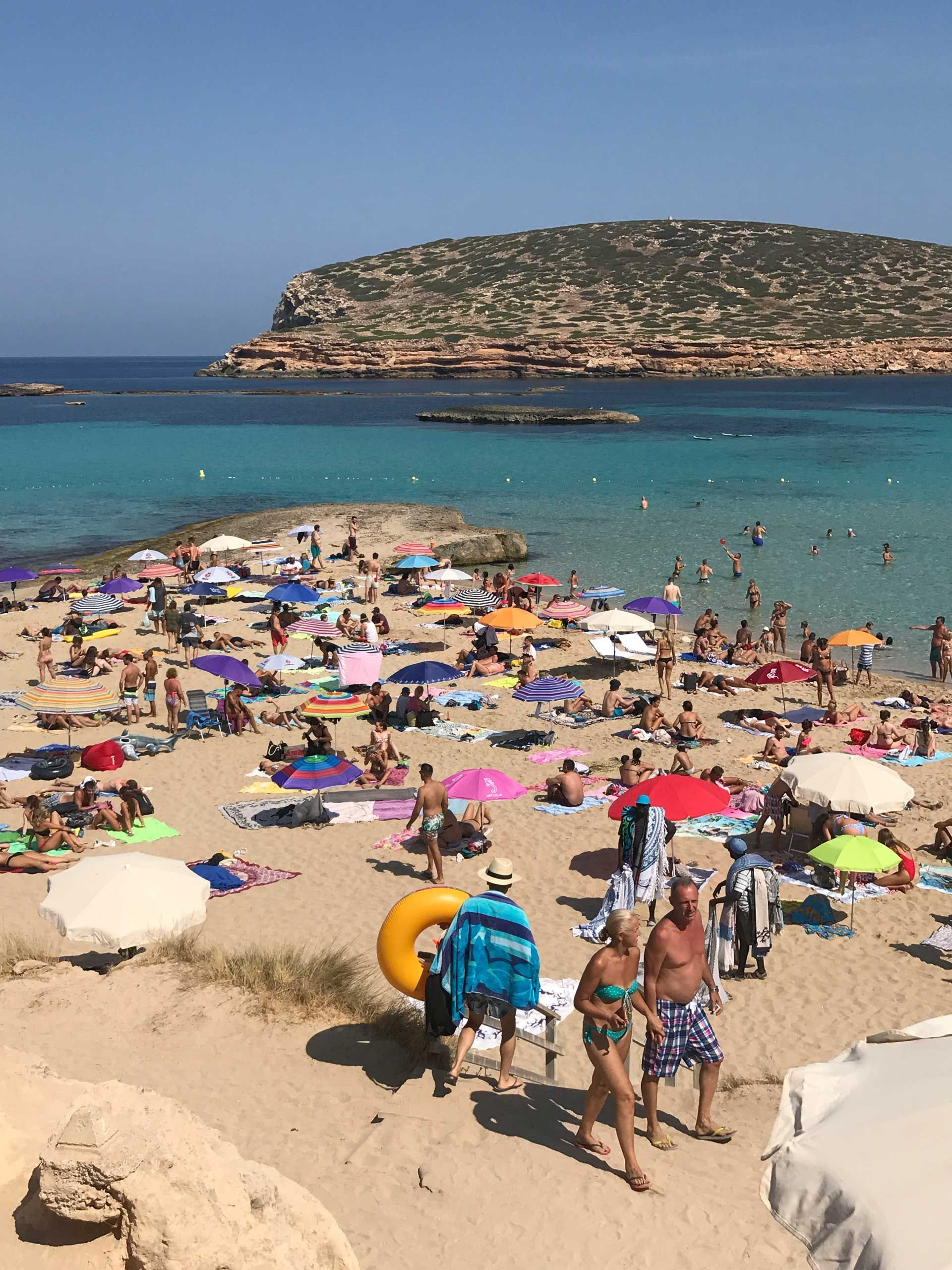 A beach filled with people and umbrellas on a sunny day