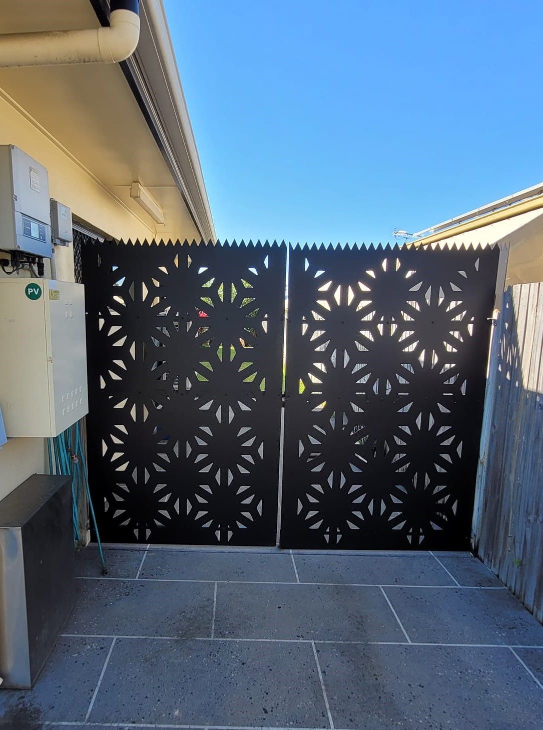 A Black Gate With A Pattern On It Is In Front Of A House — Bigdog Welding and Fabrication Pty Ltd In Currajong, QLD