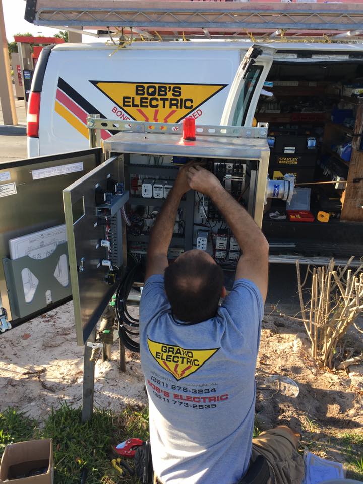 Technician works on electrical equipment beside a Bob’s Electric service truck.