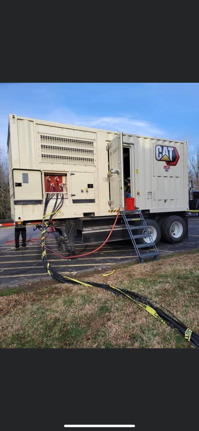 White utility truck with open side panel and hoses on the ground in a grassy outdoor area