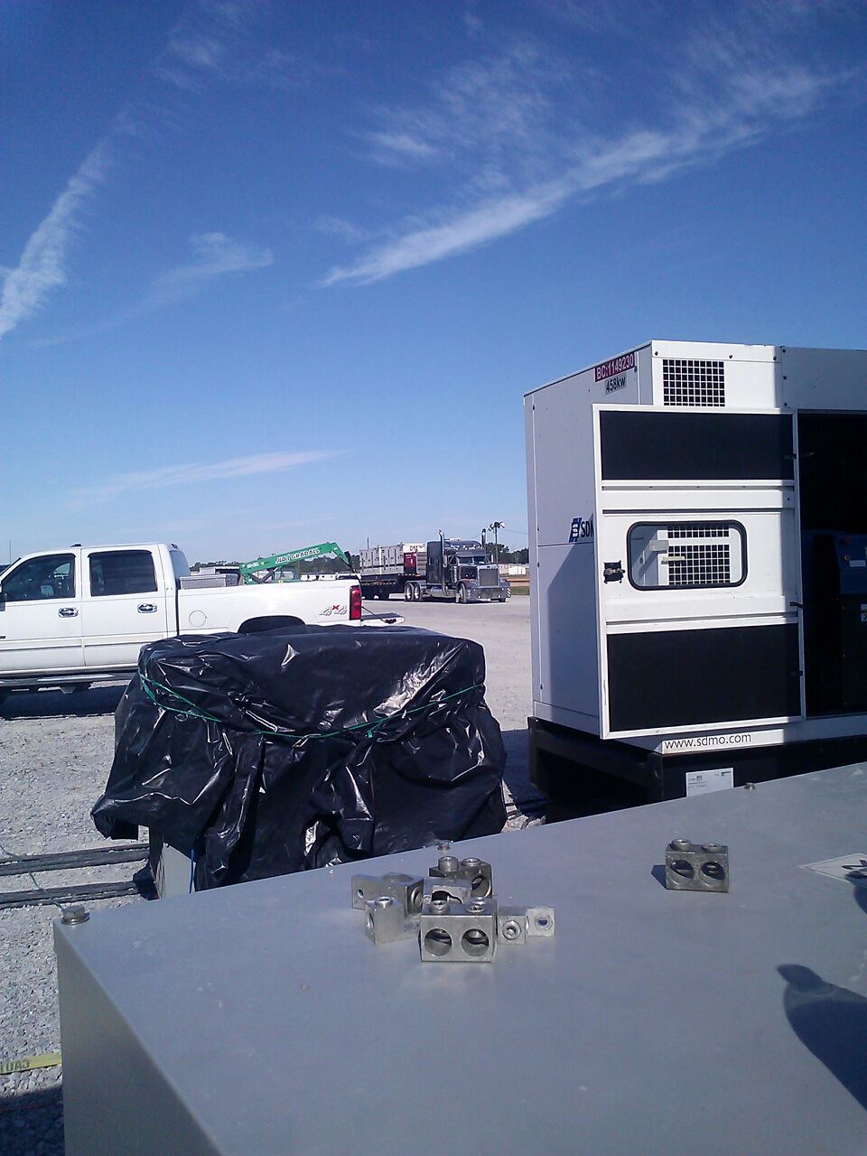 Truck and trailer in a parking lot with a covered load under a blue sky