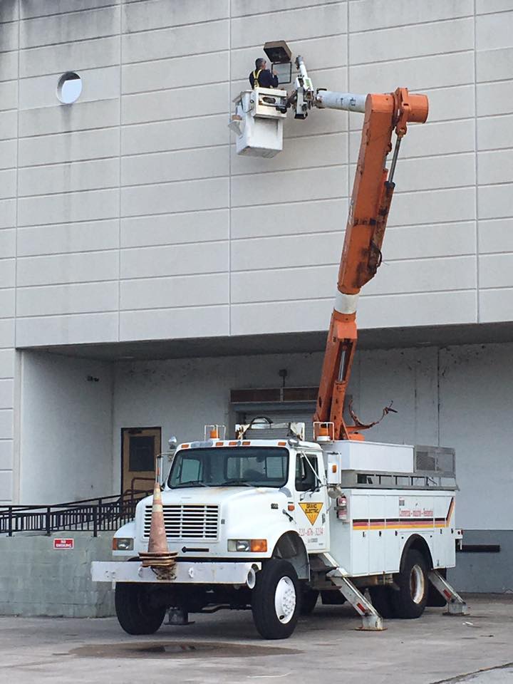 Utility truck with raised bucket lift repairing the exterior wall of a building