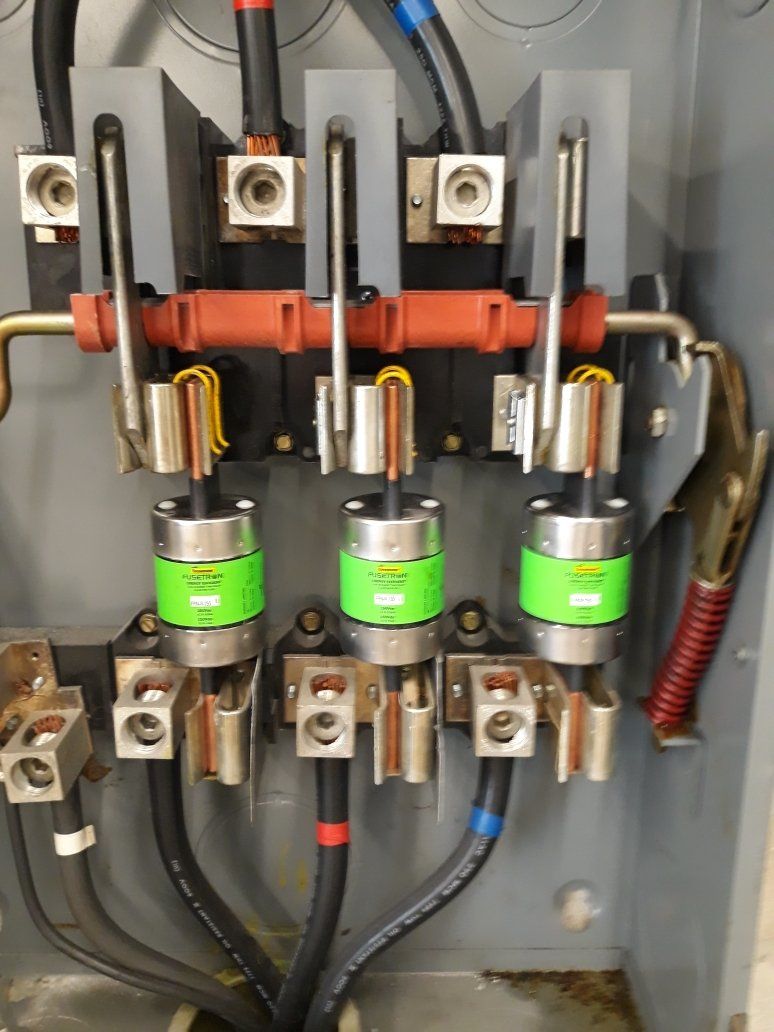 Electrical control panel with three green relays, orange bus bar, and wiring inside a gray enclosure