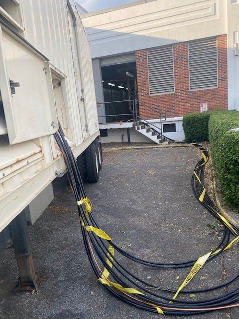 Cables draped across a driveway beside a white truck and brick building entrance