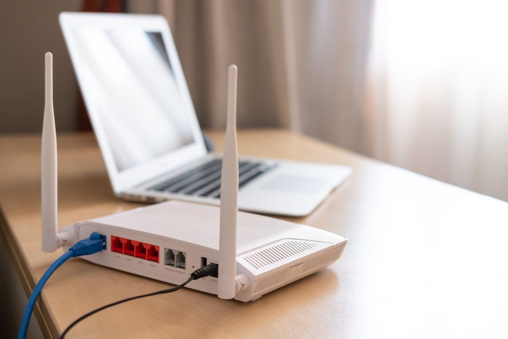 A Router is Sitting on a Wooden Table Next to a Laptop — Brightway Electrical in Ballina, NSW