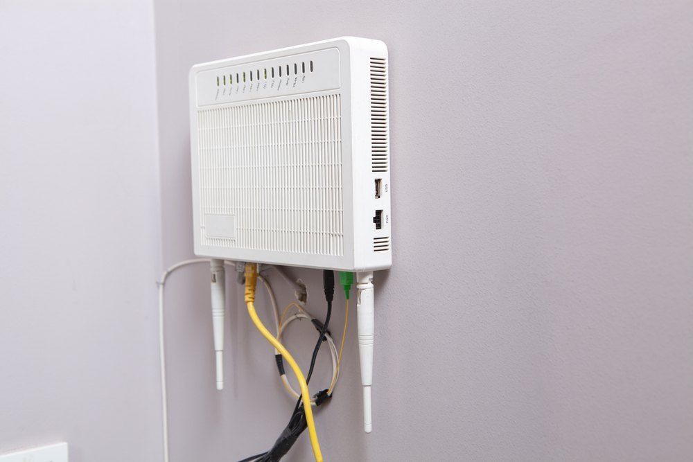A White Router is Hanging on a Wall With Wires Coming Out of It — Brightway Electrical in Lennox Head, NSW