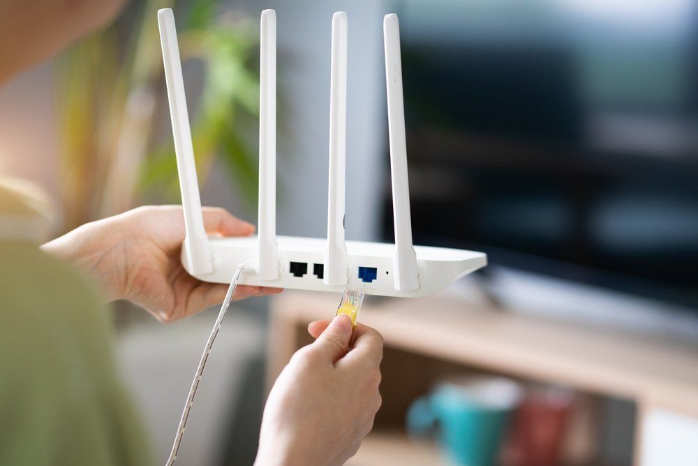 A Person is Plugging a Cable Into a Router — Brightway Electrical in Bangalow, NSW