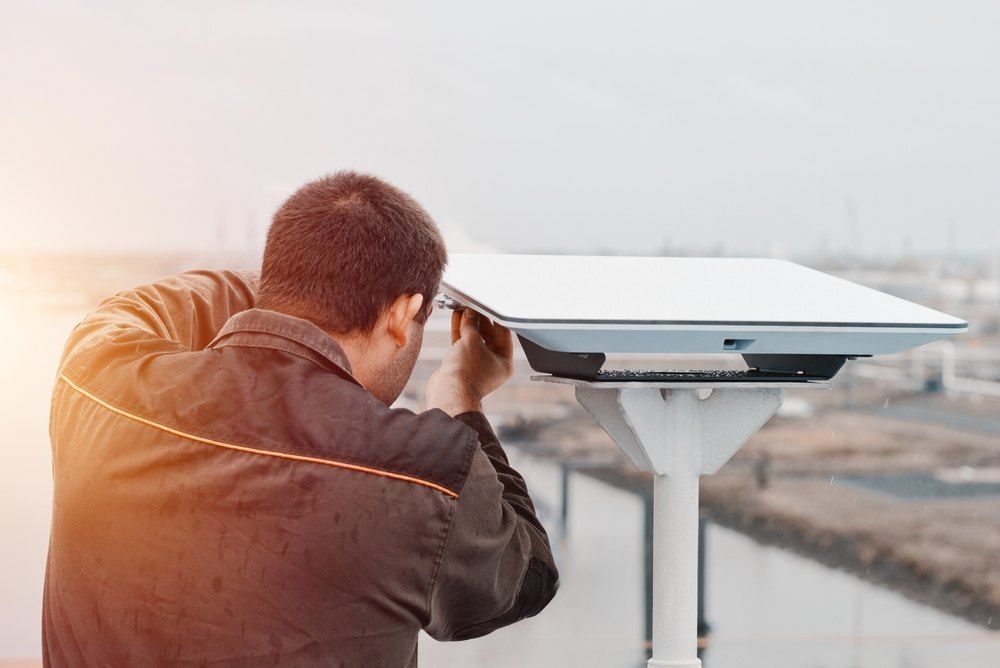 A Man is Looking Through a Telescope on Top of a Building — Brightway Electrical in Ballina, NSW