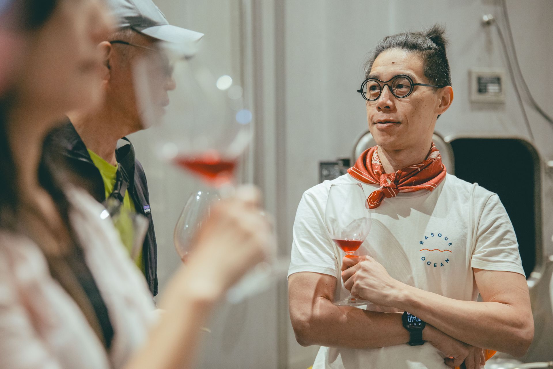 戴著眼鏡、繫著紅色圍巾的人,在社交聚會上手拿飲料