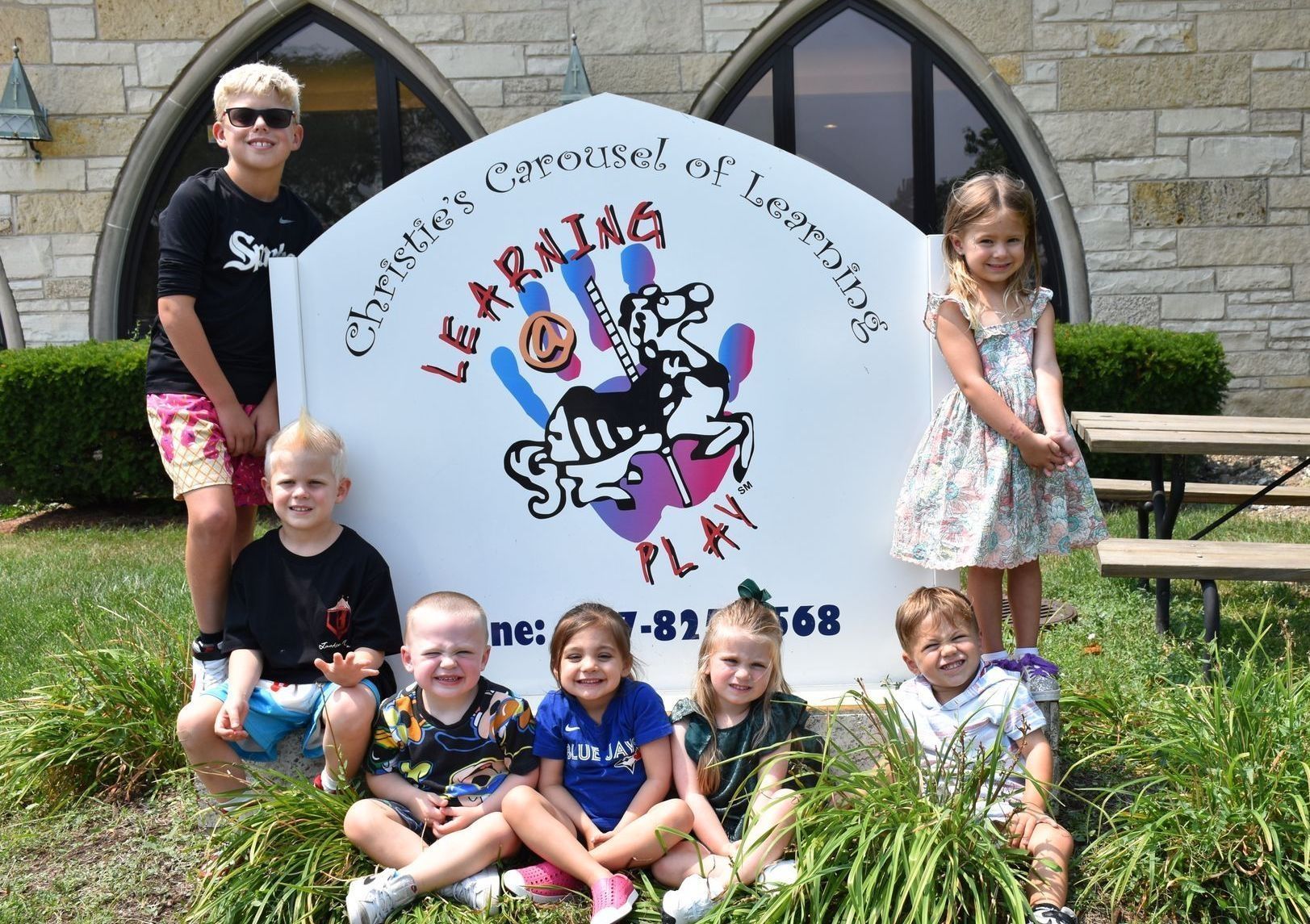 Children pose around a sign for