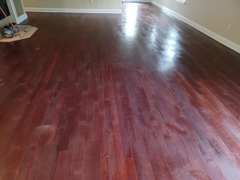 A view of a dark hardwood floor showing a noticeable difference in finish and sheen across the surface.