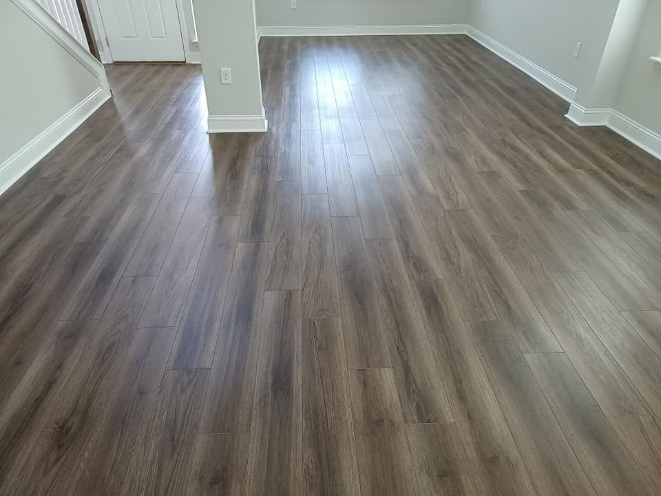 An interior view of a room with polished, dark wood-look laminate flooring, white baseboards, and a central pillar.