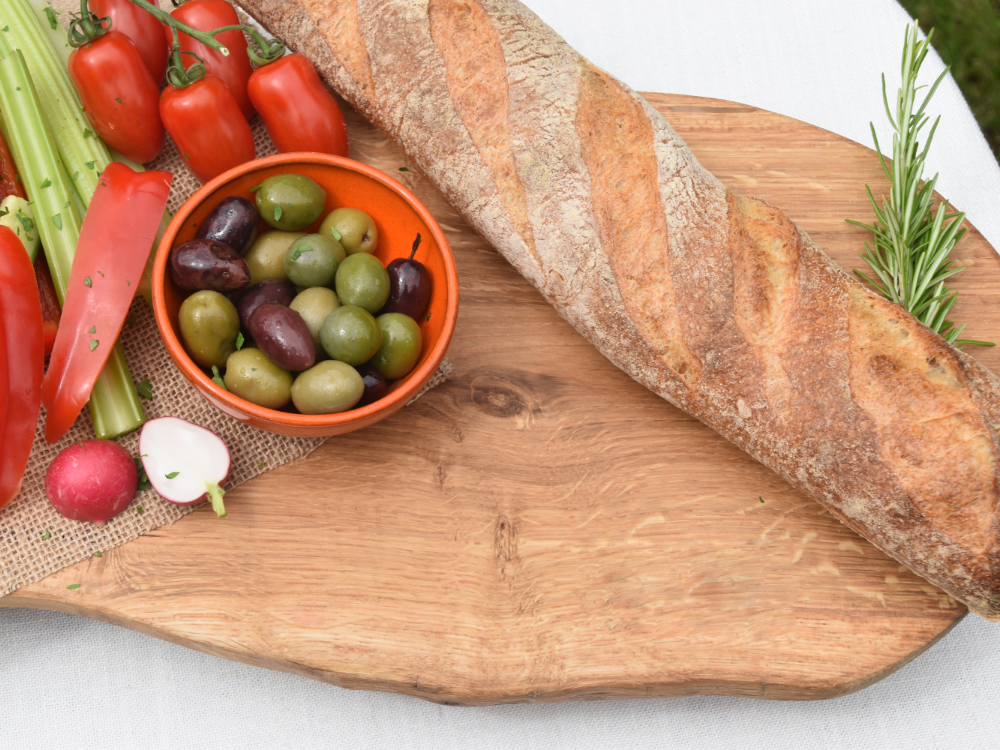 Two loaves of bread are sitting on a wooden grazing board.