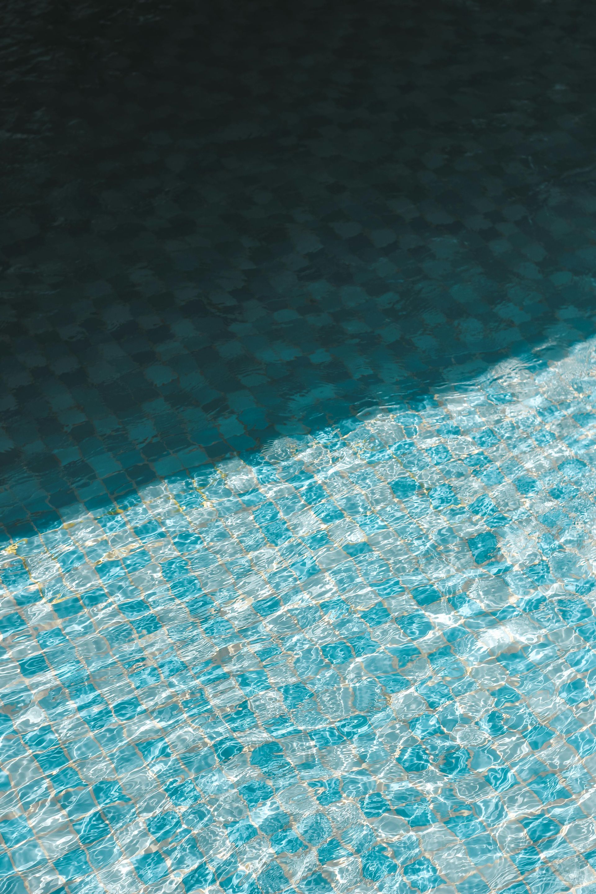 A close up of a swimming pool with blue water and a black background.
