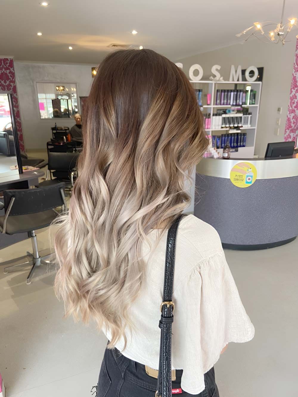 A Woman With Long Hair is Standing in a Salon — Cosmo Hair & Beauty In Nambour, QLD