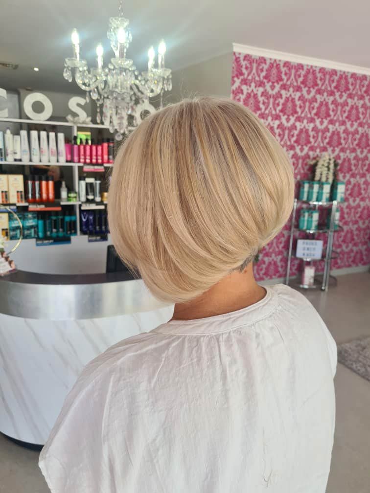 A wOman With Blonde Hair is Standing in Front of a Counter in a Salon — Cosmo Hair & Beauty In Nambour, QLD