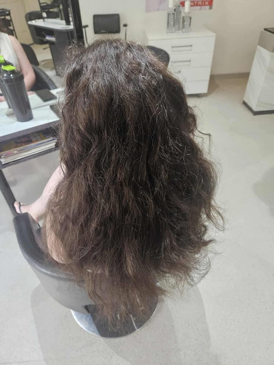 Long, Curly Dark Hair Shown From Behind In A Salon Chair — Cosmo Hair & Beauty In Nambour, QLD