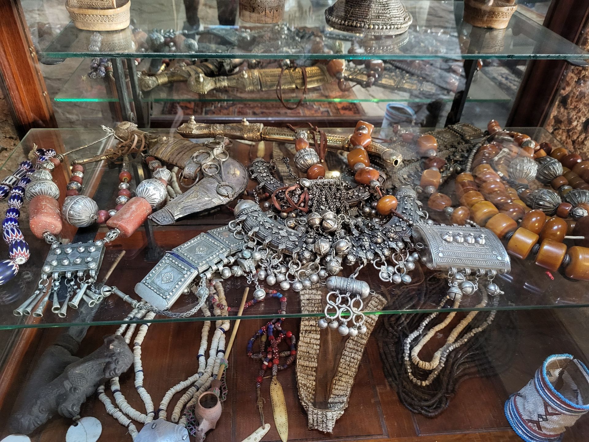 Jewelry display case with necklaces, bracelets, and ornaments in various styles, materials, and colors.