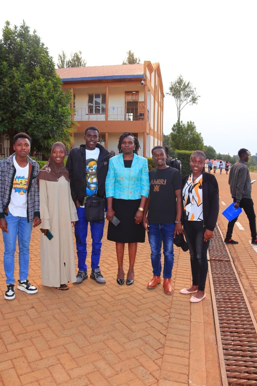 Group of people posing outdoors near a building. One woman in a blue jacket stands in front of them.