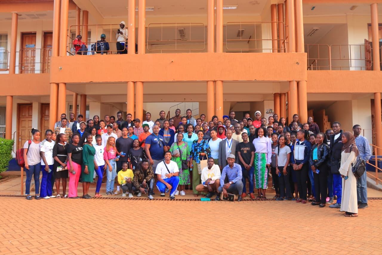 Large group of people posing in front of an orange building with a covered walkway.