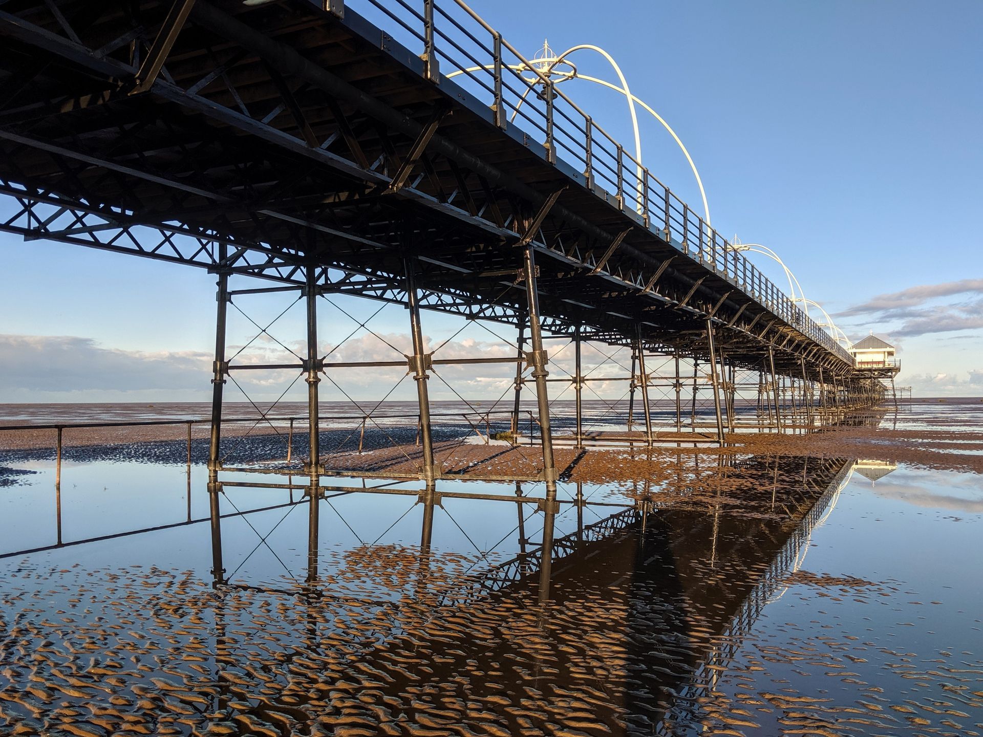Bridge over water with a white truck and cars driving on the road, with architectural pillars.