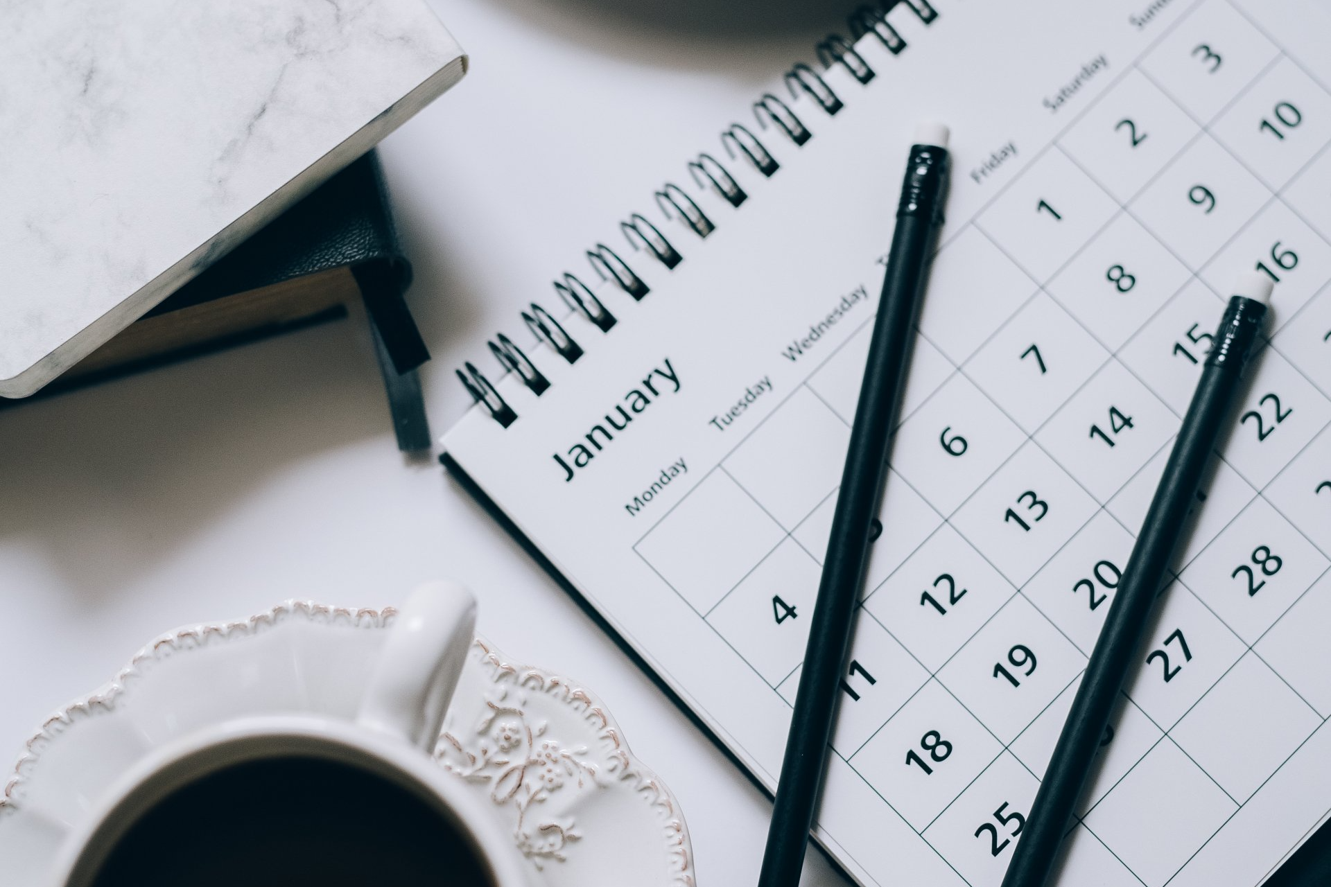 A calendar with pencils and a cup of coffee on it