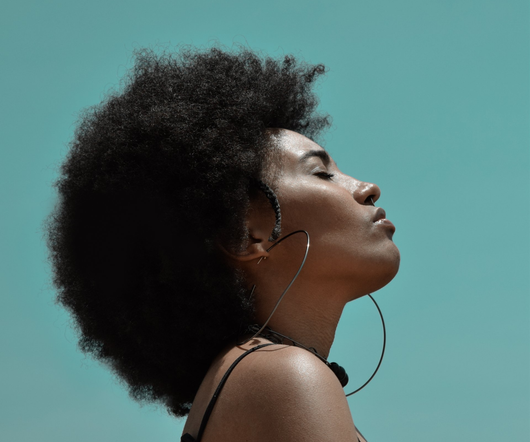 A woman with an afro and hoop earrings is looking up at the sky.