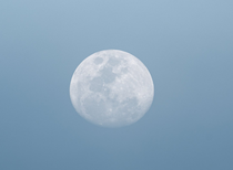 A full moon is visible in a clear blue sky