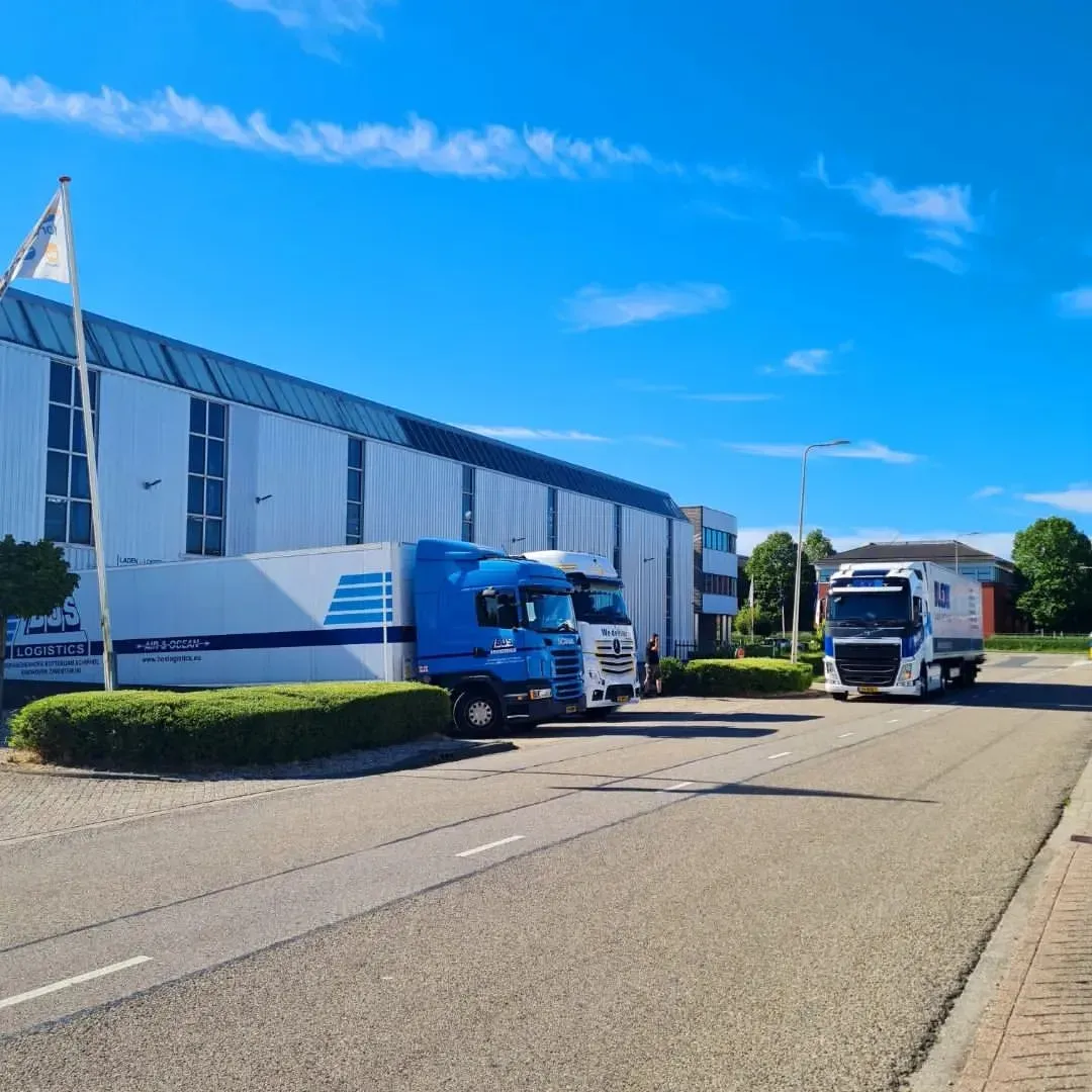 Op een zonnige dag staan ​​twee vrachtwagens voor een gebouw geparkeerd