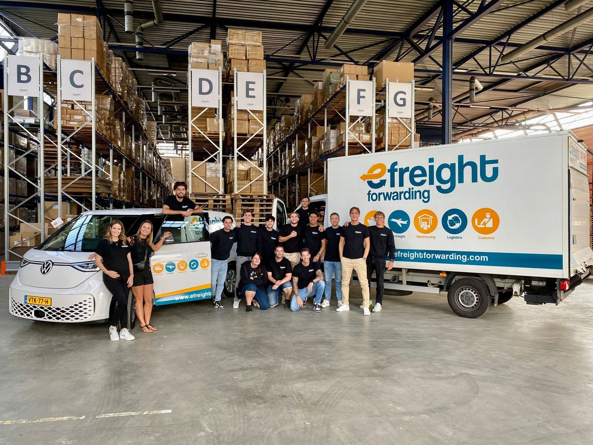 een groep mensen poseert voor een foto voor een vrachtvrachtwagen.