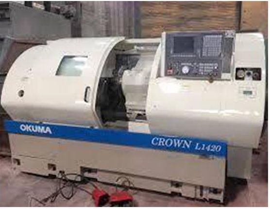 An Okuma Crown L1420 CNC lathe in a workshop, featuring a white metal body with a blue horizontal control panel stripe.