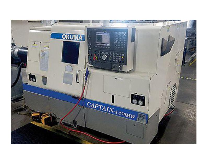 An off-white Okuma Captain-L370MW CNC lathe machine with a digital control panel, standing in a factory setting.