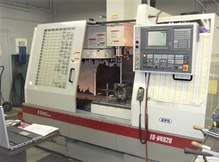 Une fraiseuse CNC industrielle blanche et rouge trône dans un atelier, ses portes coulissantes ouvertes.