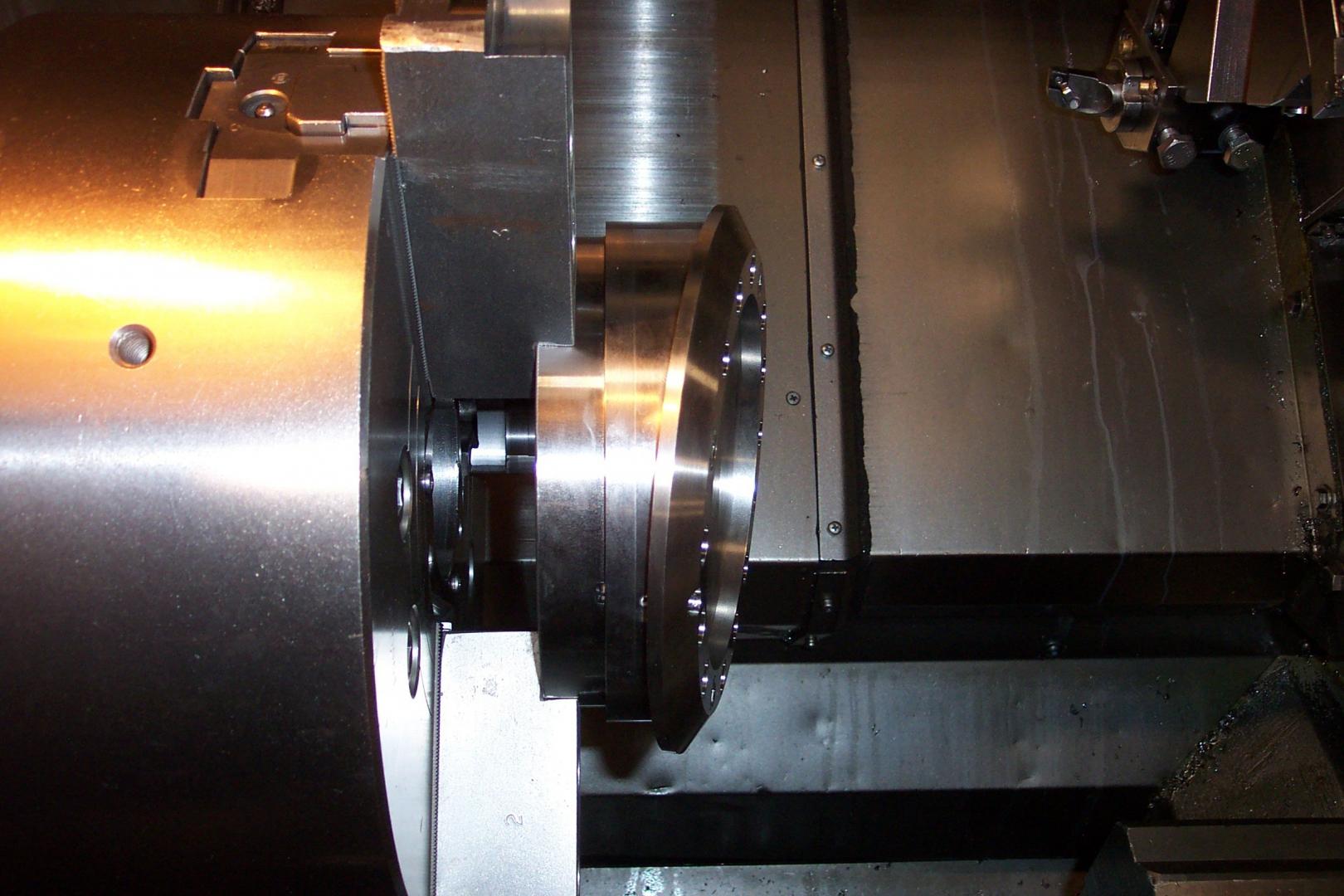 Une pièce métallique fixée dans le mandrin d'un tour à commande numérique, avec un outil de coupe positionné pour l'usinage.