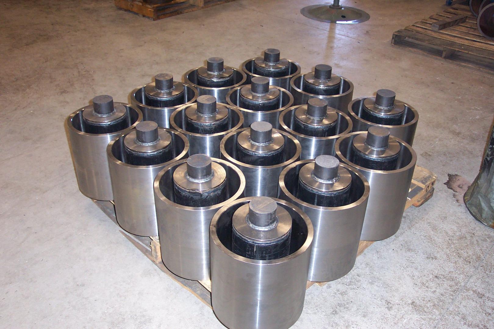 A collection of metal cylindrical components arranged in a grid on a pallet in a workshop.