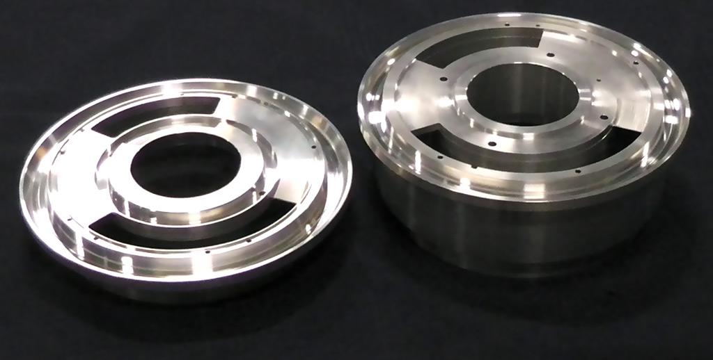 Two machined metal circular industrial components, one flat and one deeper, sitting on a black background.