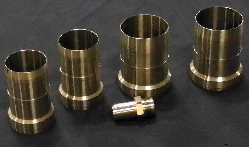 Four cylindrical metal sleeves arranged with a small threaded fitting on a dark, flat surface.