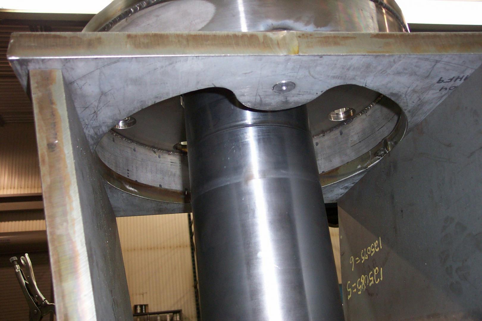 A close-up view of a large industrial machine component with a smooth, dark, cylindrical vertical pillar.