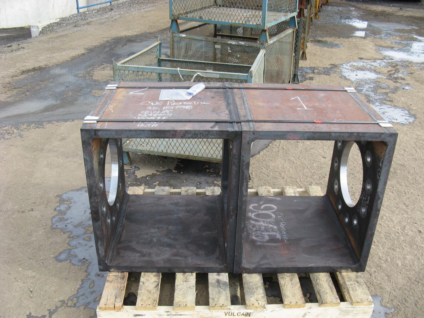 Une structure métallique à double chambre avec des ouvertures circulaires, posée sur une palette en bois à l'extérieur.