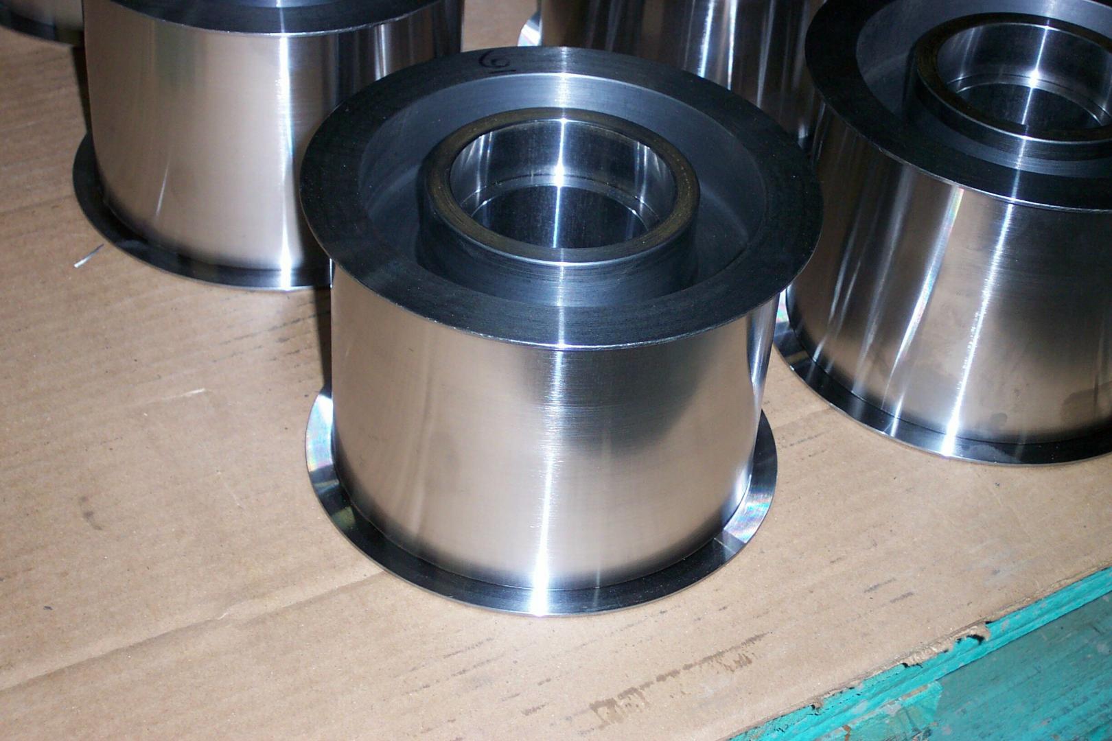 Composants industriels cylindriques en métal disposés sur une surface plane et texturée.