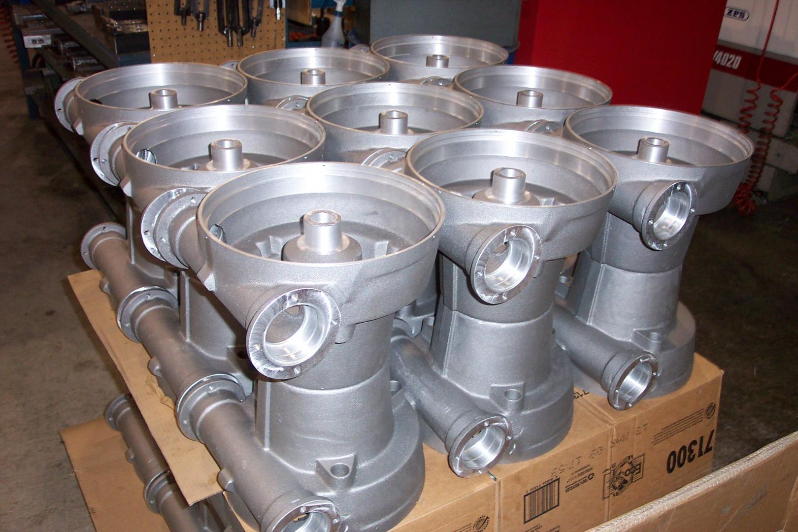 Un ensemble de composants industriels en aluminium moulé, posés sur des cartons dans un entrepôt.