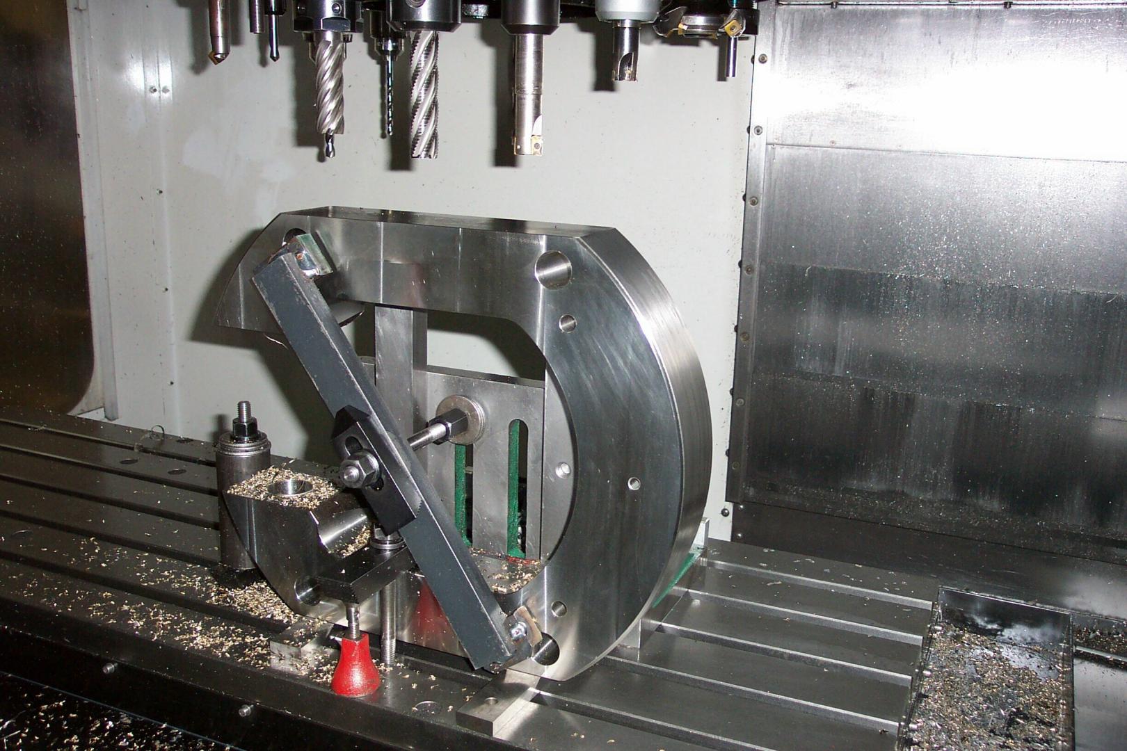 Pièce métallique fixée dans une fraiseuse CNC avec des outils de coupe montés sur la broche au-dessus de la surface de travail.