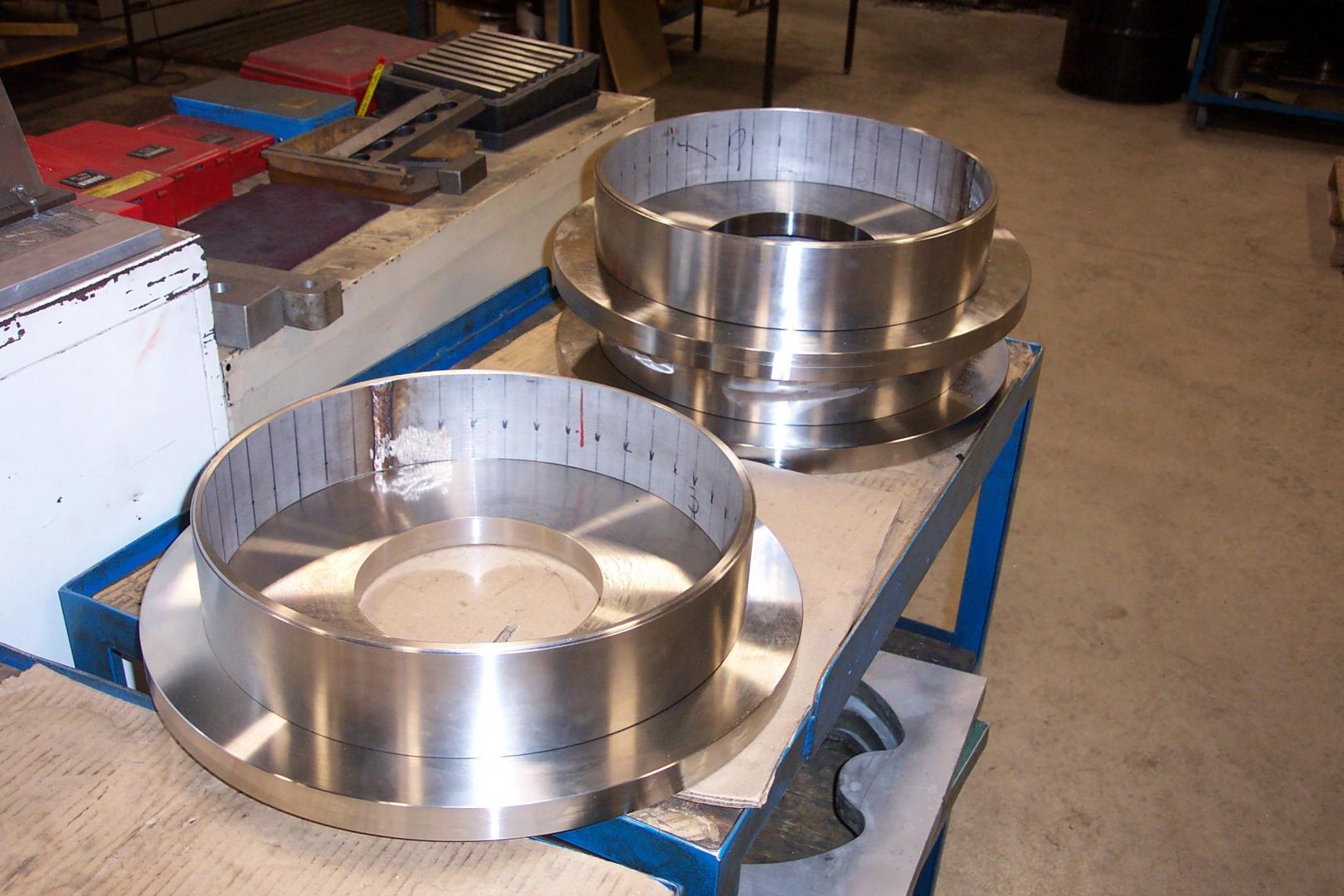 Deux grandes pièces circulaires en métal usiné sont posées sur un établi dans un atelier.