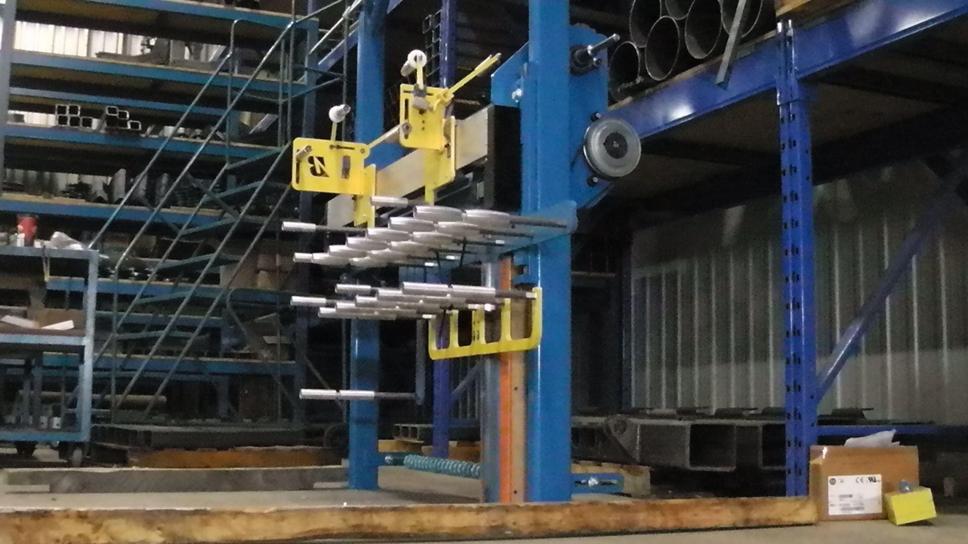 A blue industrial storage rack with rows of horizontal metal arms, holding various metal bars, in a warehouse setting.