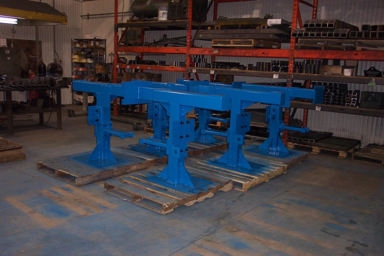 Bright blue industrial metal stands on wooden pallets in a warehouse.