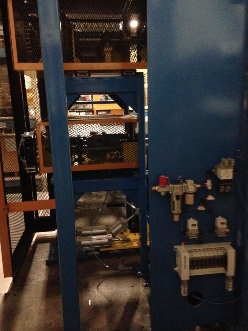 A blue industrial machine frame with a pneumatic filter and control valves mounted on a side panel.
